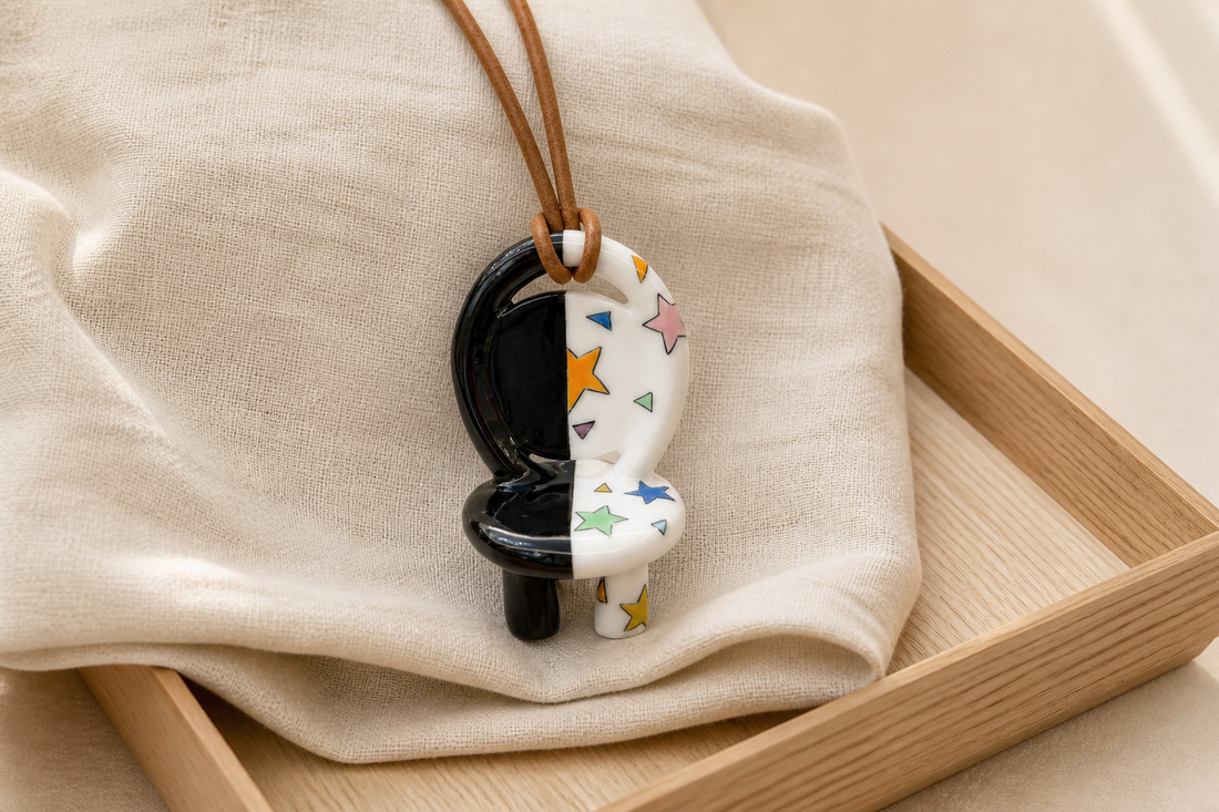 Starry Night ceramic chair necklace resting on folded linen in a wooden tray